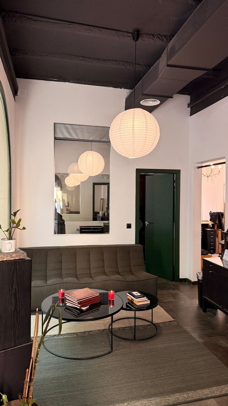 Sala de espera de Casa Tatu: sofá verde, lámparas de papel y puerta verde